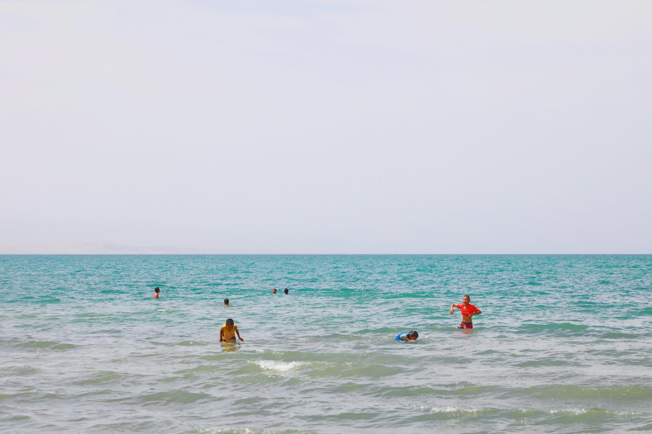 8.夏日，持续高温，孩子们在家长的陪伴下在和硕县金沙滩景区开心的戏水消暑降温，在蔚蓝的湖水中一起享受夏日的清凉。（和硕县纪委监委  罗华静 摄）.png